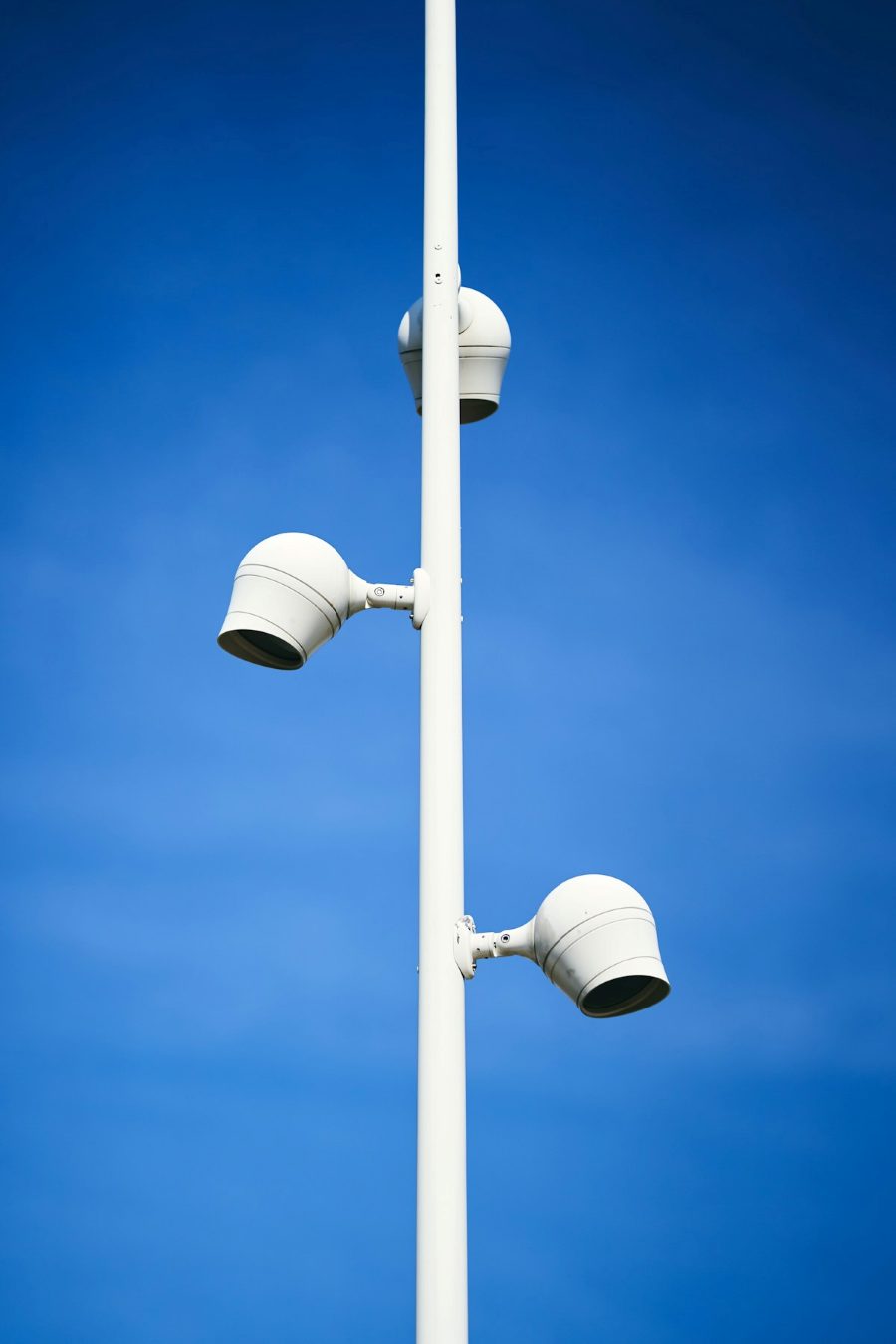 Poste branco com câmeras de monitoramento contra o céu azul